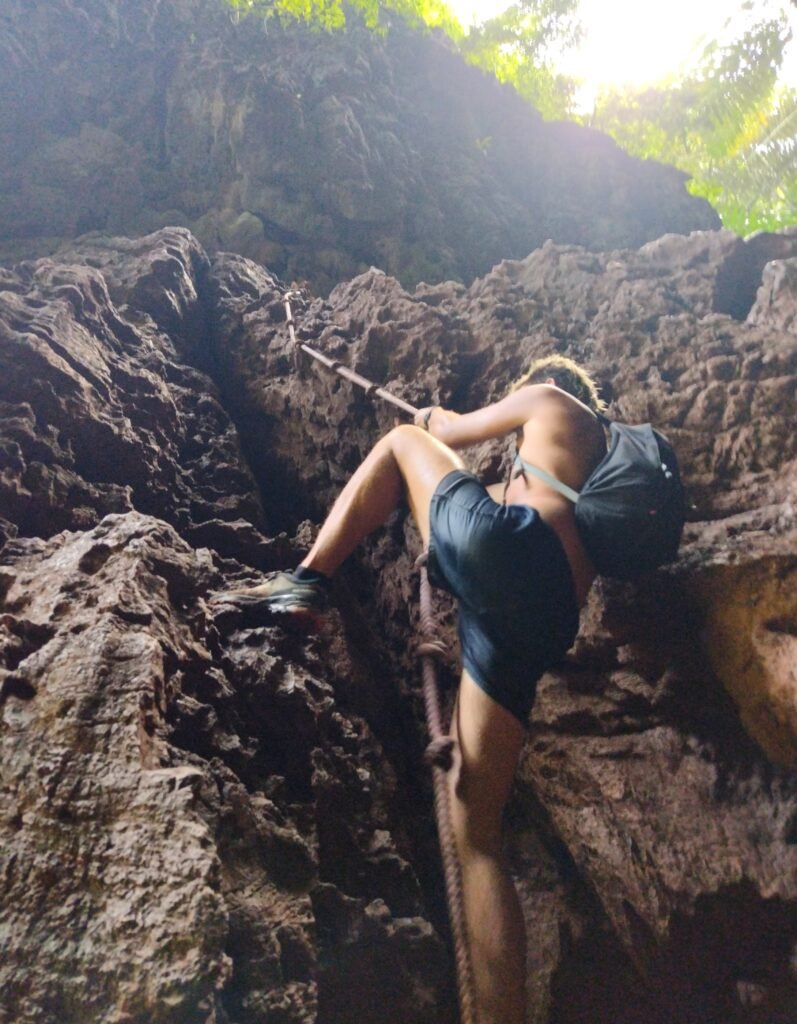 Man climbing up rope at Railay Beach Lagoon