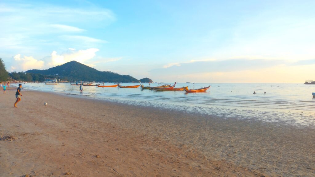 Ko Tao Beach with boats and children playing football
